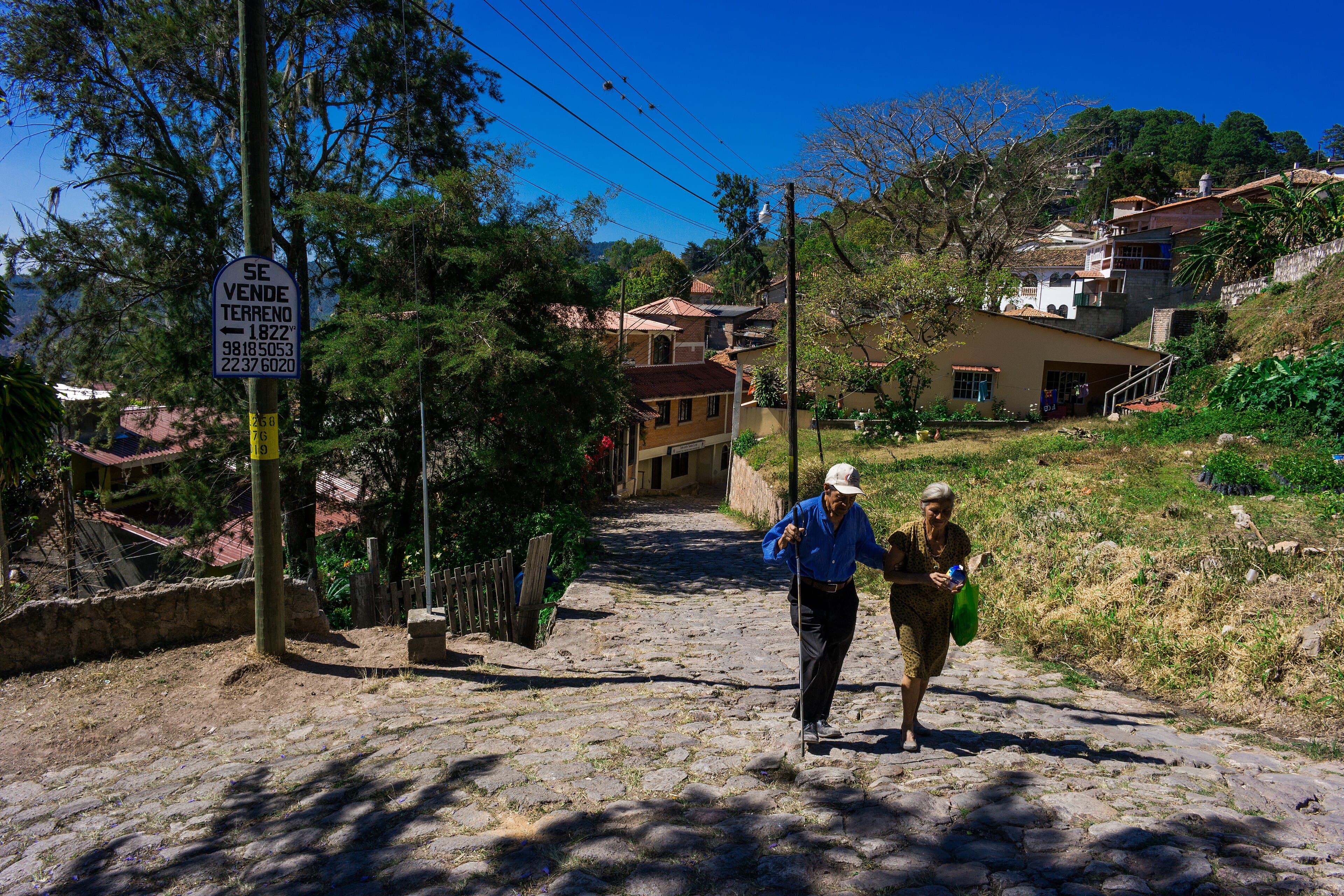Calle empedrada en cuesta de Santa Lucía, con casas de teja bajando hacia el valle