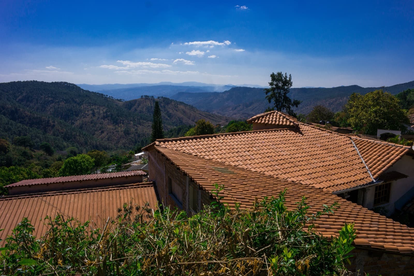 Techos de teja de Santa Lucía en primer plano, con las montañas boscosas del valle detrás